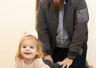 Chiropractor providing gentle pediatric adjustment to a smiling young girl.
