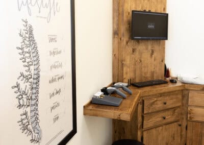 Reception area at Ignite Chiropractic with wooden furniture and a wall-mounted monitor.